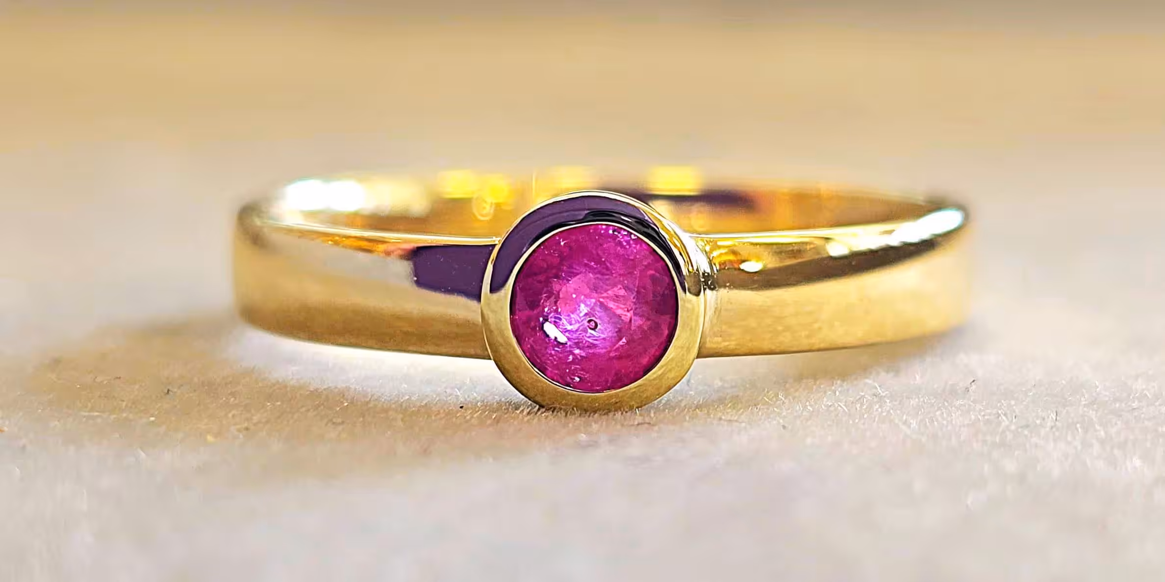 Verlobungsring aus Gelbgold mit rundem, pinkfarbenem Rubin in moderner Zargenfassung – handgefertigter Goldring mit elegantem, zeitlosem Design.