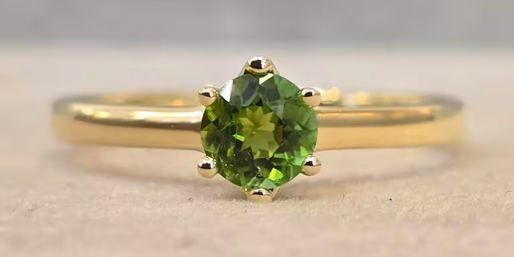 Trauringe selber schmieden: Grüner Edelstein in Goldring.