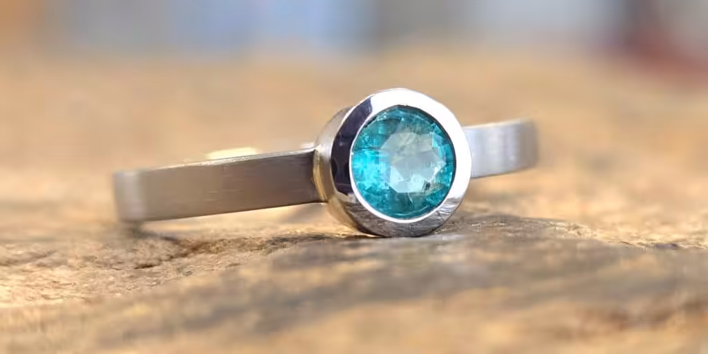Ring mit einem runden, blauen Topas in einer schlichten, Fassung und Ringschiene aus Platin