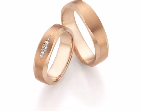 Zwei goldene Trauringe mit Struktur und Diamanten, handgefertigt.