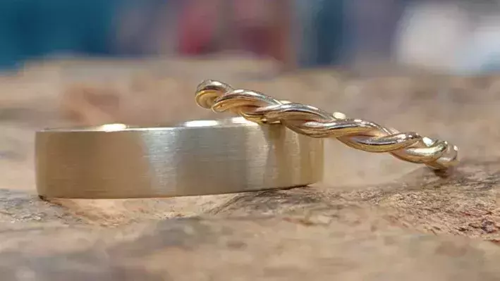 Von Kursteilnehmern selbst geschmiedete Trauringe: ein breiter, mattierter Ring und ein filigran geflochtener Ring.