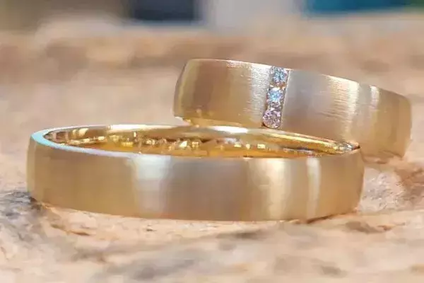 Selbst geschmiedete Trauringe aus Gelbgold, einer davon mit einer Reihe kleiner Brillanten.