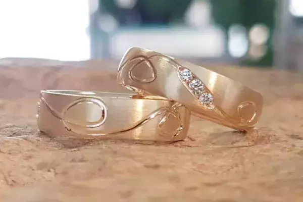 Selbst geschmiedete Trauringe aus Gelbgold mit Schlangenmotiven und drei Brillanten.