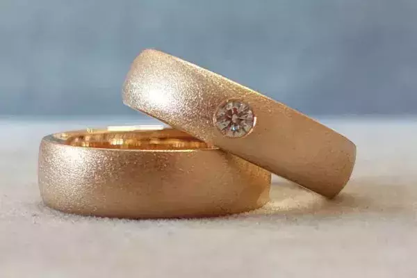 Von einem Hochzeitspaar selbst geschmiedete Trauringe aus Gold, einer davon mit Brillant.