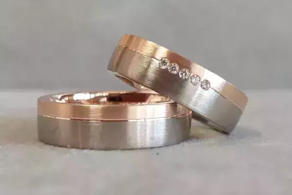 Bicolor-Trauringe aus Roségold und Weißgold mit matter Oberfläche und fünf Brillanten.