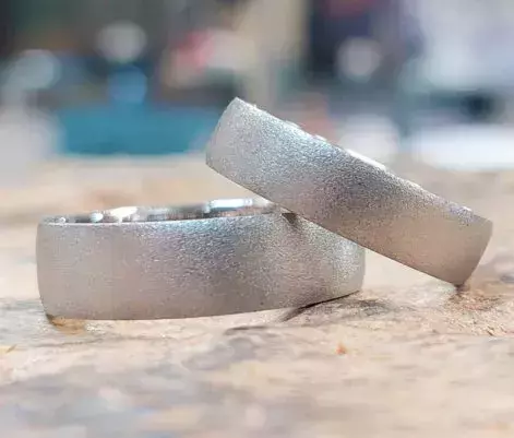 Von Kursteilnehmern selbst geschmiedete Trauringe aus Weißgold mit fein strukturierter matter Oberfläche.