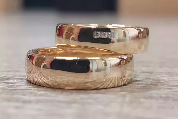 Zwei hochglänzende Trauringe aus Gold, von einem Hochzeitspaar selbst geschmiedet.