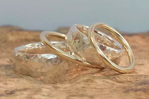 Selbst geschmiedete Trauringe aus Weißgold mit gehämmerter Oberfläche und passenden Vorsteckringen aus Gelbgold.