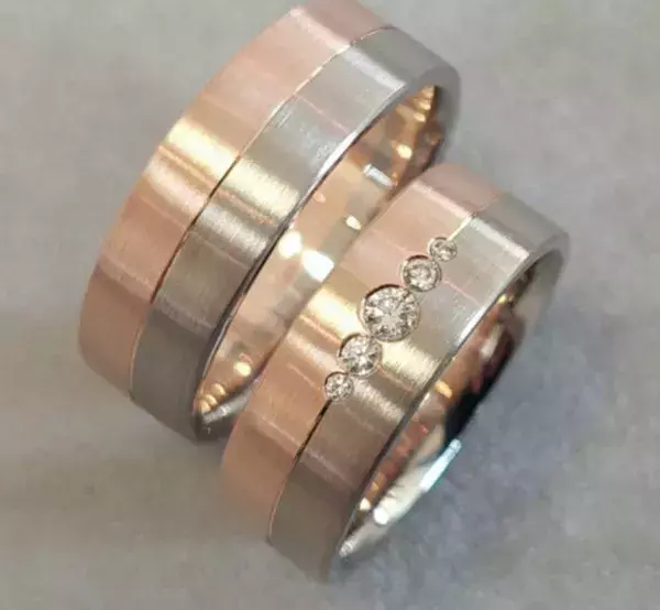 **Alt-Text:** Selbst geschmiedete Trauringe aus Roségold und Weißgold mit Brillanten, angefertigt von einem Paar im Trauringkurs der Schmuckwerkstatt Trolese in Dreieich.