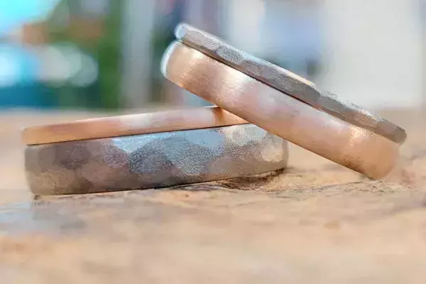 Selbst geschmiedete Trauringe aus Roségold und Weißgold mit strukturierter Oberfläche aus der Schmuckwerkstatt Trolese in Dreieich.