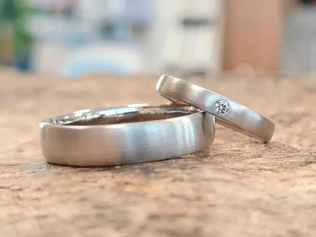 Selbst geschmiedete Trauringe mit matter Oberfläche und eingefasstem Diamant
