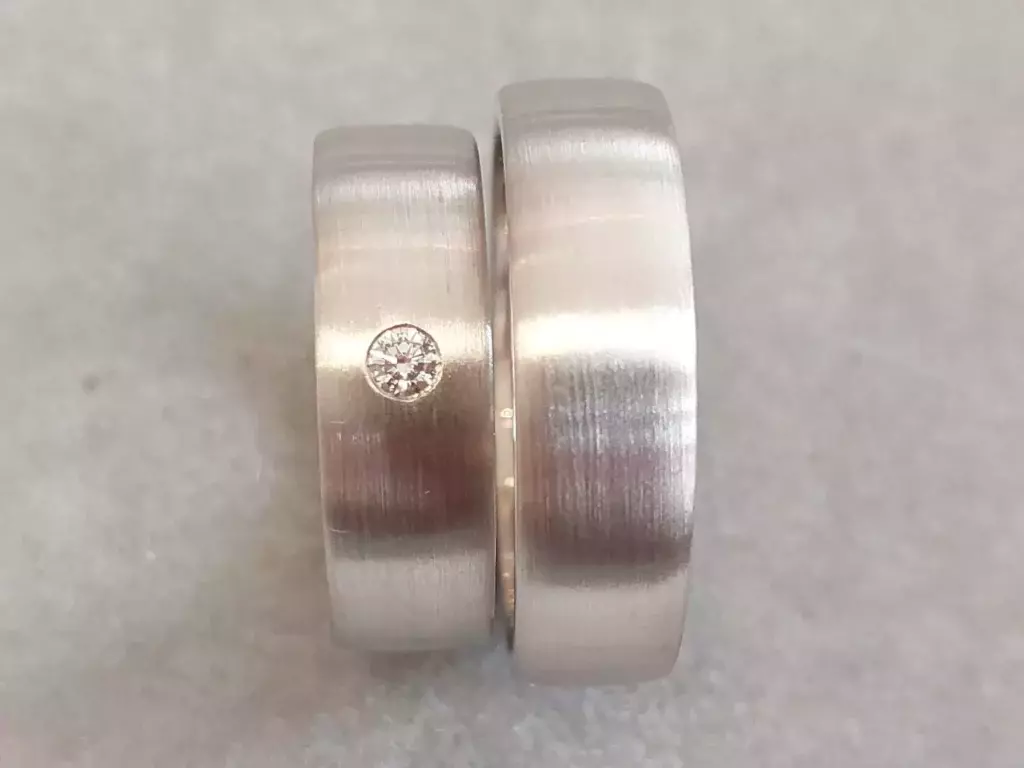 Selbst geschmiedete Trauringe mit matter Oberfläche und bündig eingefasstem Diamant