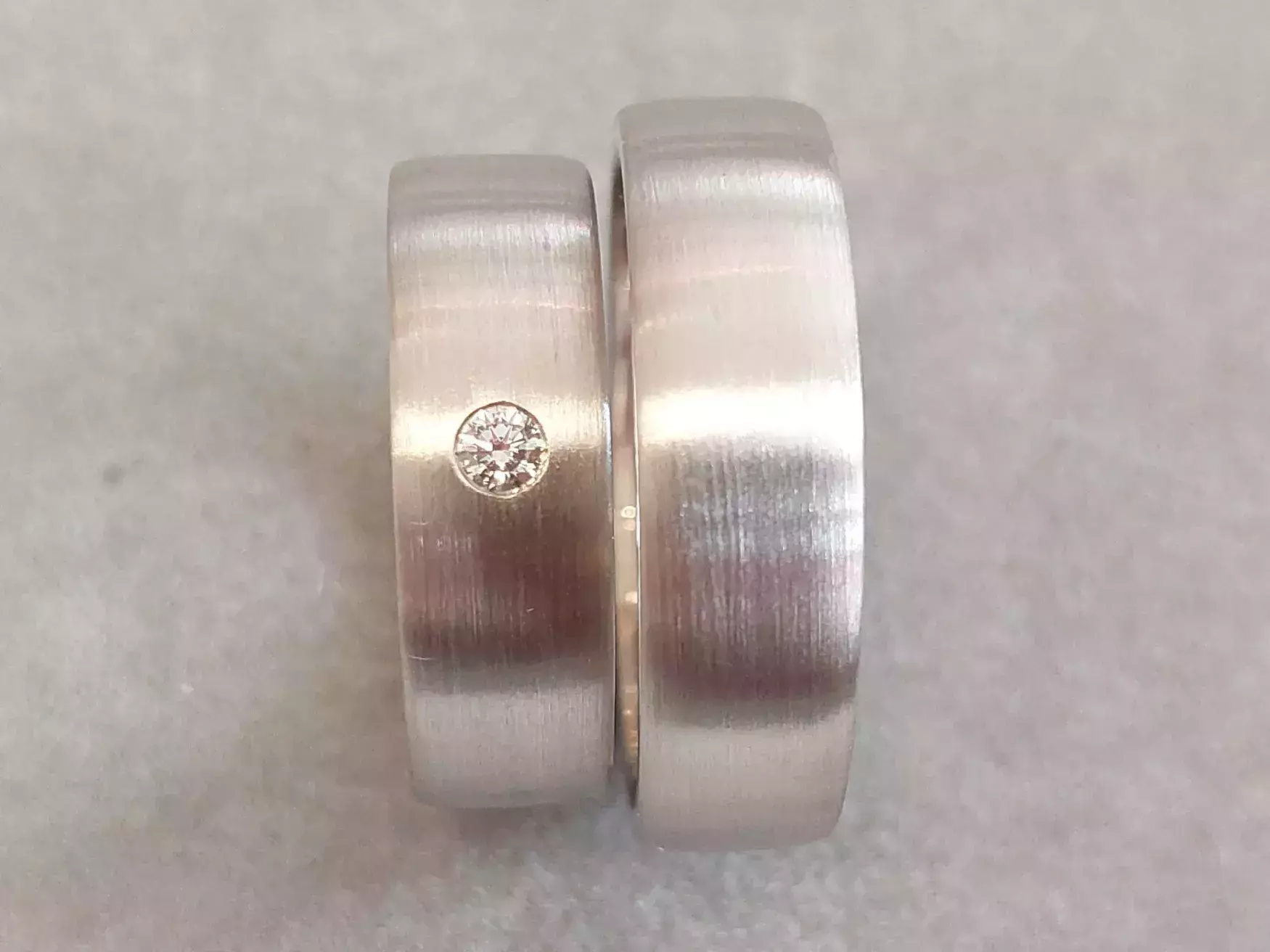 Selbst geschmiedete Trauringe mit matter Oberfläche und bündig eingefasstem Diamant