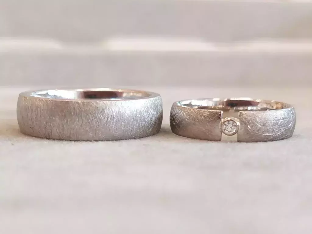 Selbst geschmiedete Trauringe aus dem Trauringkurs mit strukturierter Oberfläche und eingesetztem Diamant