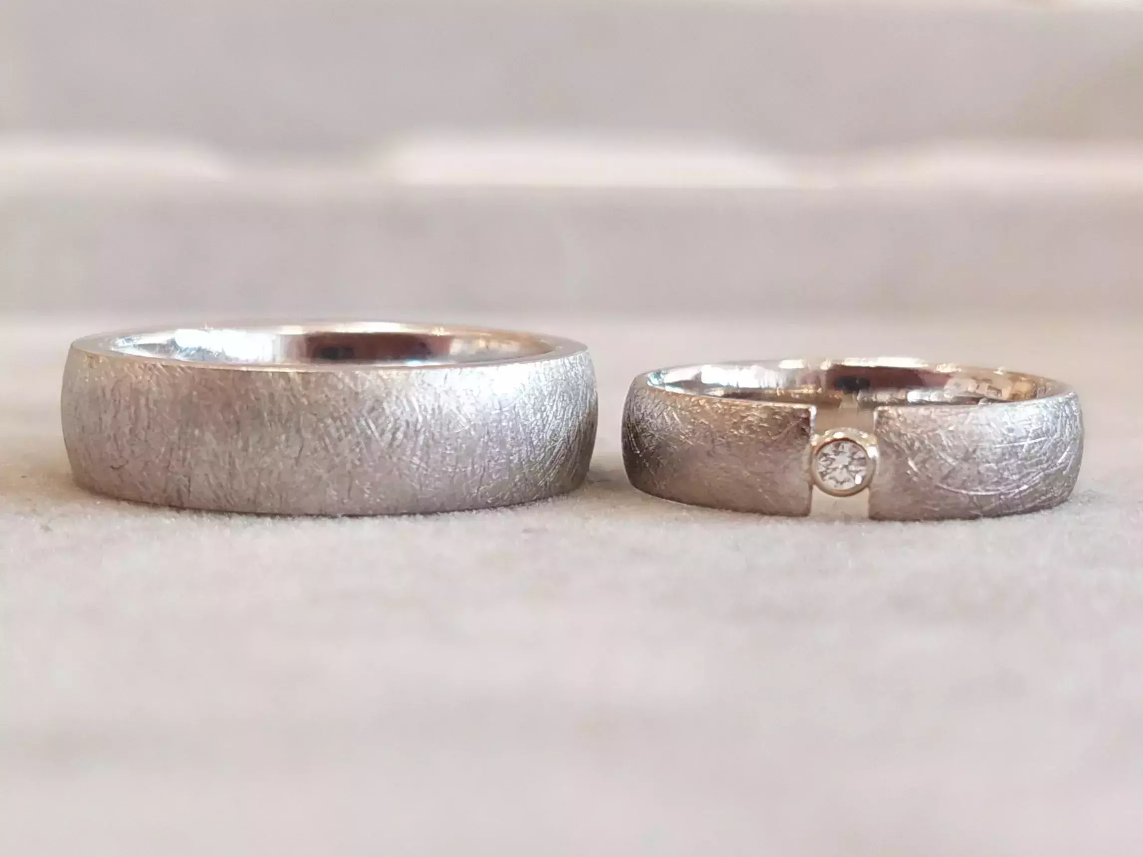 Selbst geschmiedete Trauringe aus dem Trauringkurs mit strukturierter Oberfläche und eingesetztem Diamant