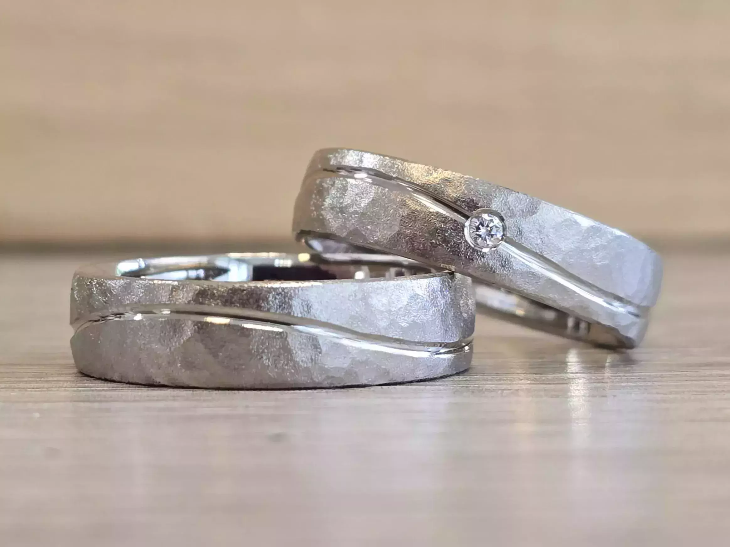 Selbst geschmiedete Trauringe mit strukturierter matter Oberfläche, geschwungener Linie und Diamant
