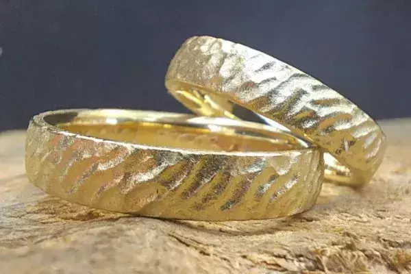 Selbst geschmiedete Trauringe aus Gelbgold mit markanter Hammerschlagstruktur.