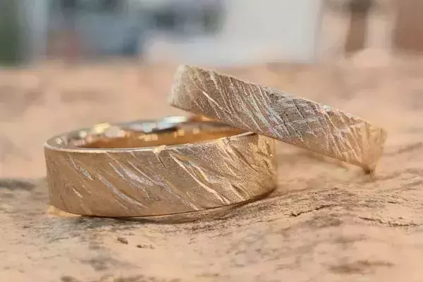 Zwei selbst geschmiedete Trauringe aus Gold mit diagonal strukturierter Oberfläche