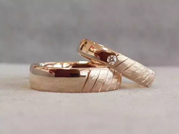 Selbst geschmiedete Trauringe aus Roségold mit Rillenstruktur und Brillant.