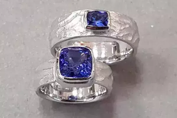 Selbstgeschmiedete Trauringe aus Weißgold mit blauen Topasen, gefertigt im Trauringkurs der Schmuckwerkstatt Trolese.